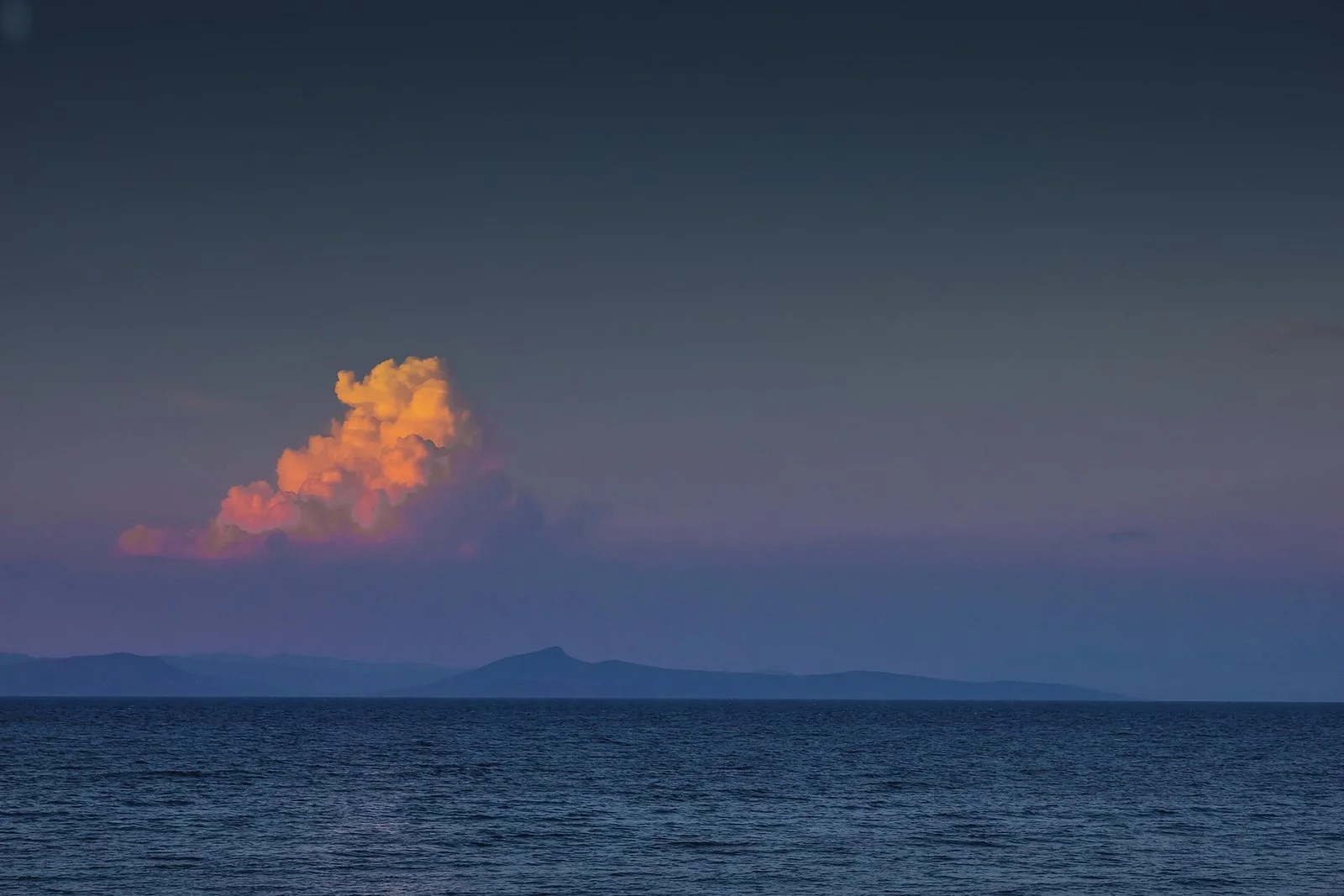 夕方の光を受けた雲と、穏やかなエーゲ海、遠くの島影。