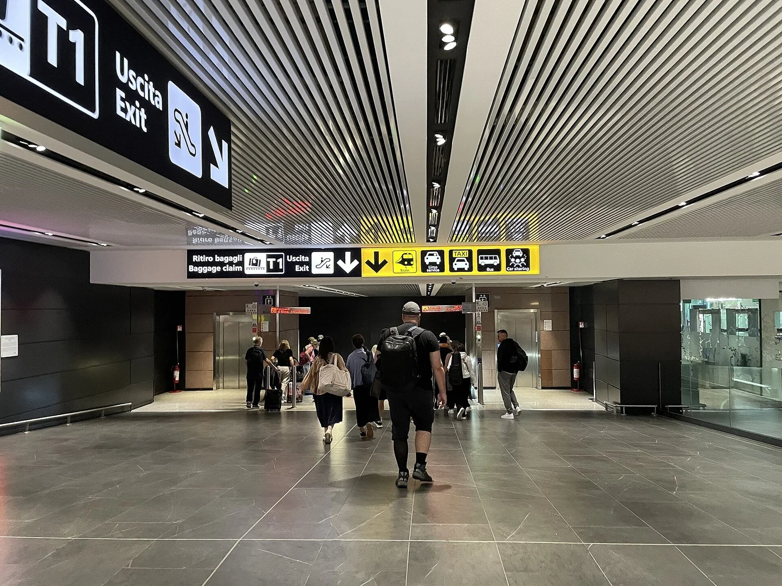 フィウミチーノ空港第1ターミナルの通路。天井の黄色い案内に列車やタクシーの乗り場が出ている。